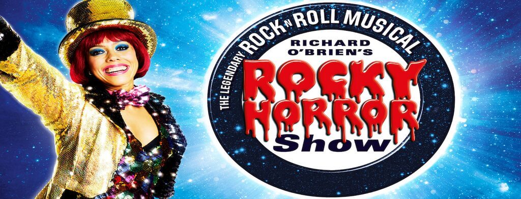 Banner advertising The Rocky Horror Show, with a red haired lady on the left dressed in gold sequins and a gold top hat.